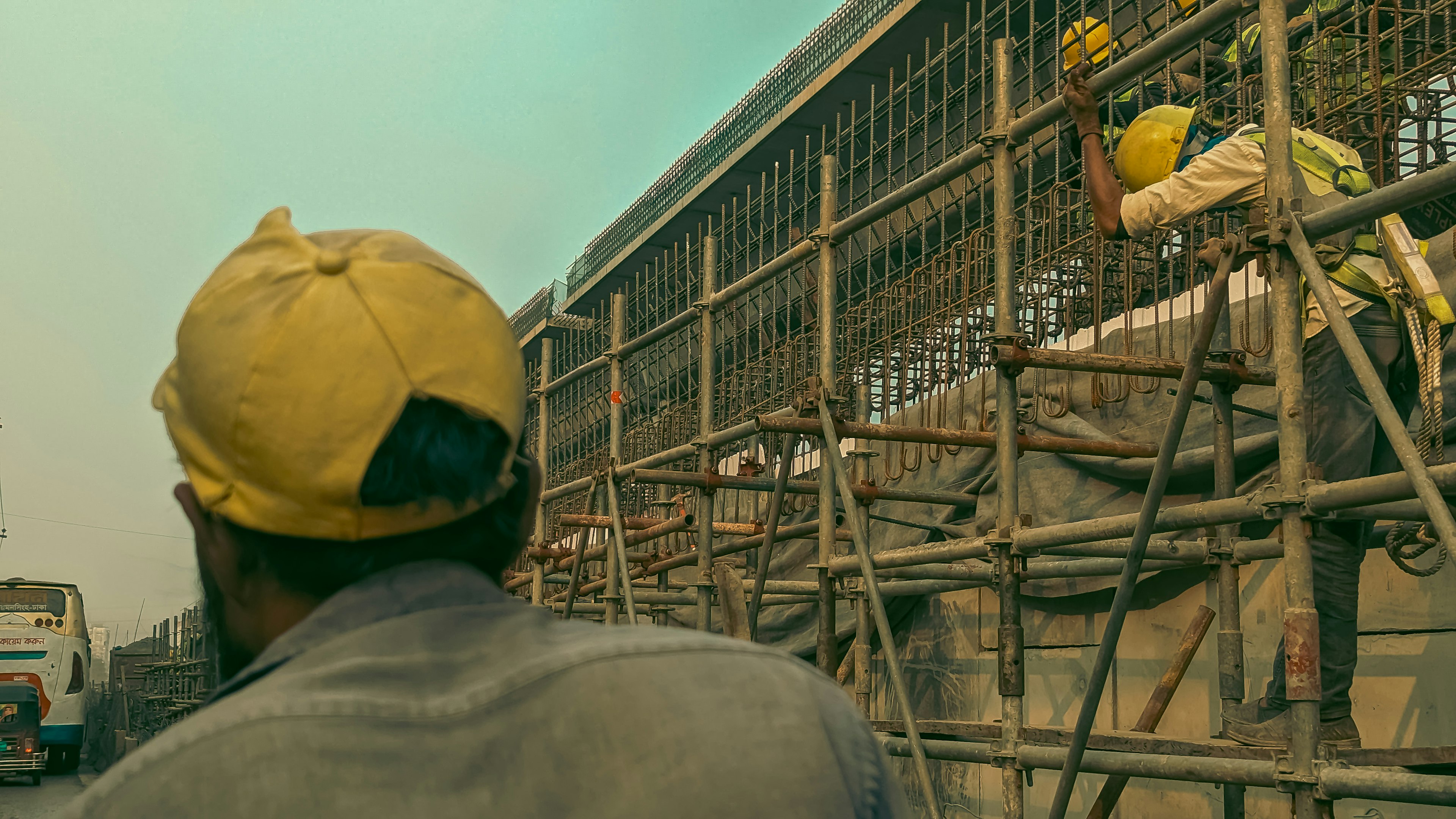 F6HVR3oWxzU_a_man_standing_on_a_scaffold_in_front_of_a_buildin_4032x2268